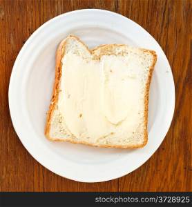 top view of bread and butter sandwich on white plate on wooden table