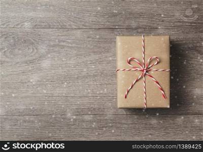 Top view of brown gift box with red rope on wooden background with copy space.