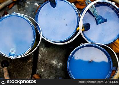 Top view of bucket with blue paint and brush