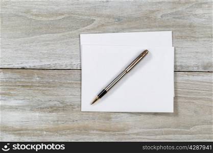Top view of business envelope and writing pen on rustic white wooden desktop