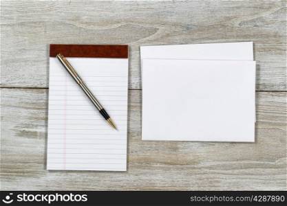 Top view of business envelope and writing pen with notepad on rustic white wooden desktop