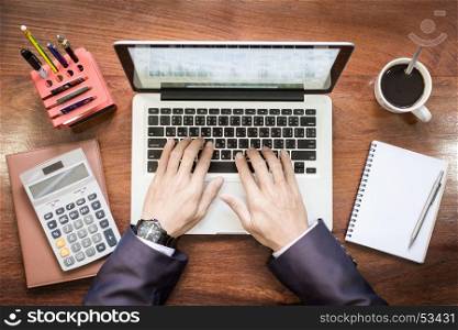 Top view of business man hands working on laptop or tablet pc on wooden desk.