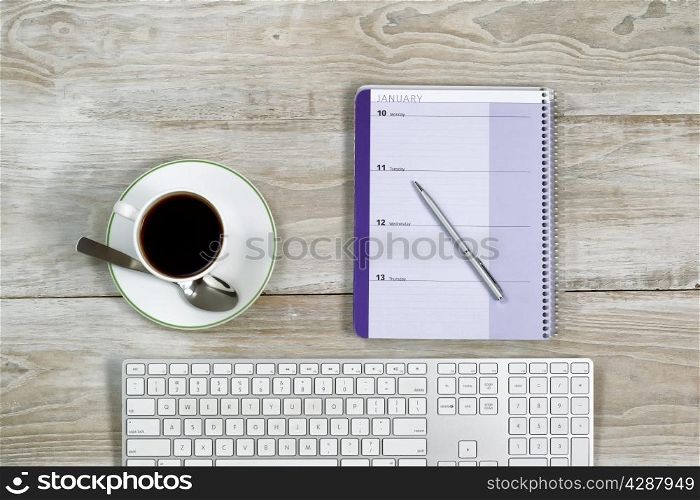 Top view of business office objects consisting of calendar, pen, computer keyboard and cup of coffee on white wooden desktop