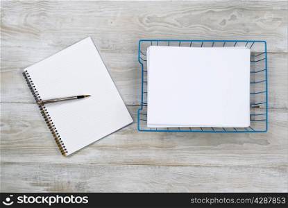 Top view of business office objects consisting of inbox, notepad and pen on rustic white wooden desktop