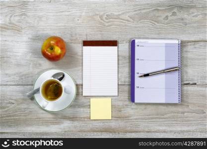 Top view of business office objects with food and drink on rustic white wooden desktop