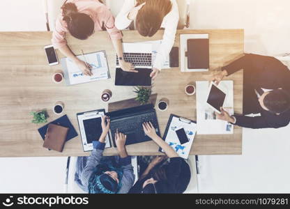 Top view of businessman executive in group meeting with other businessmen and businesswomen in modern office with laptop computer, coffee and document on table. People corporate business team concept.