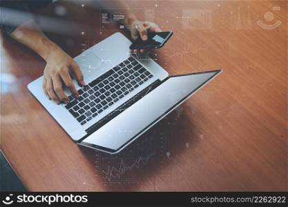 top view of businessman hand using on smart phone and laptop computer with digital business strategy diagra layer on wooden desk as concept