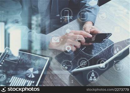 top view of businessman hand using smart phone,mobile payments online shopping,omni channel,digital tablet docking keyboard computer,documnets,in modern office on wooden desk,virtual interface icons screen