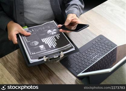 top view of businessman hand using smart phone,mobile payments online shopping,omni channel,digital tablet docking keyboard computer,documnets,in modern office on wooden desk