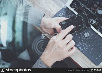 top view of businessman hand using smart phone,mobile payments online shopping,omni channel,digital tablet docking keyboard computer in modern office on wooden desk,virtual interface icons screen