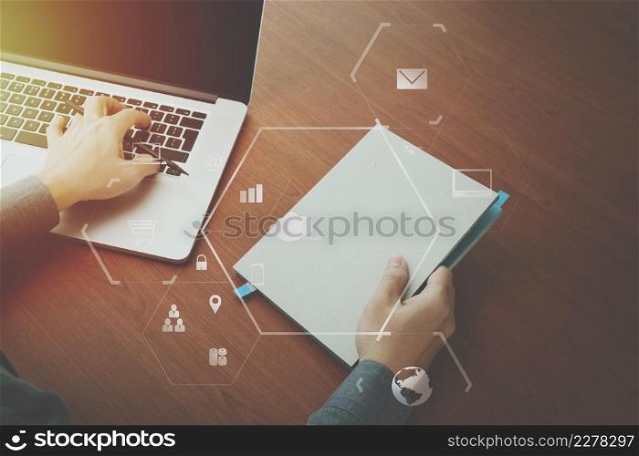 top view of businessman hand working with laptop computer and book with VR business strategy concept on wooden desk