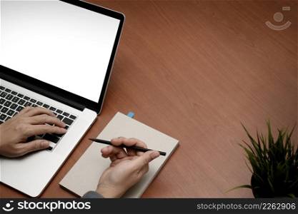 top view of businessman hand working with new modern blank screen computer on blank book on wooden desk as concept