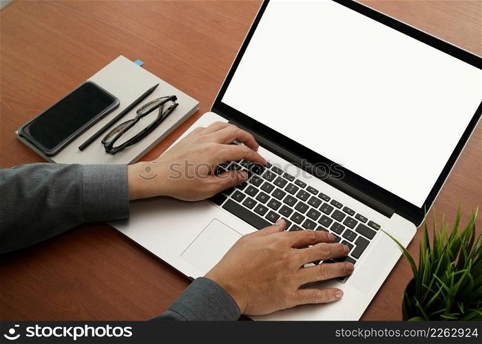 top view of businessman hand working with new modern blank screen computer and smartphone on blank book on wooden desk as concept