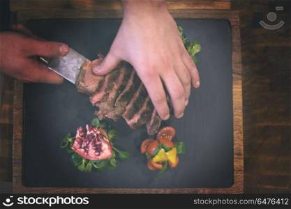 top view of Chef hands in hotel or restaurant kitchen serving beef steak with vegetable decoration. top view of Chef hands serving beef steak