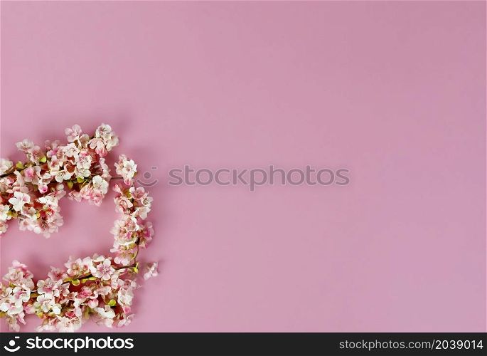 Top view of cherry blossoms on a pink background for Mothers Day or Easter holiday concept