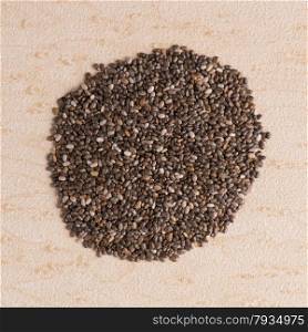 Top view of chia seeds against brown vinyl background.