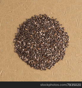 Top view of chia seeds against brown vinyl background.