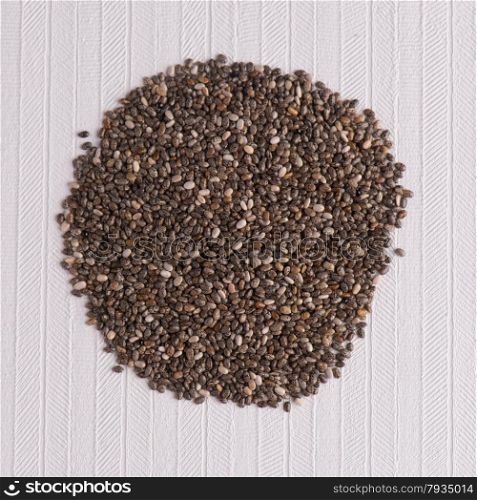 Top view of chia seeds against white vinyl background.