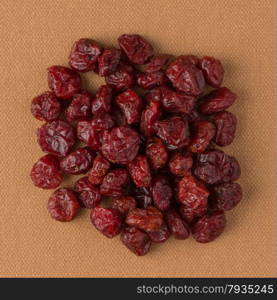 Top view of circle of dried cranberries against brown vinyl background.