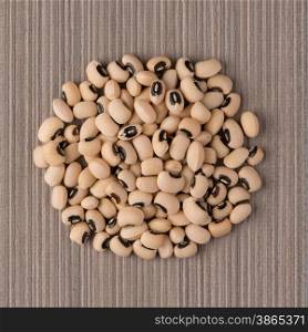 Top view of circle of white beans against brown vinyl background.