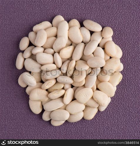 Top view of circle of white beans against purple vinyl background.