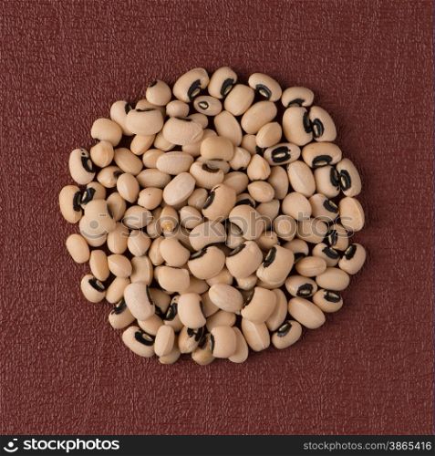 Top view of circle of white beans against red vinyl background.