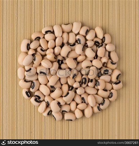 Top view of circle of white beans against yellow vinyl background.