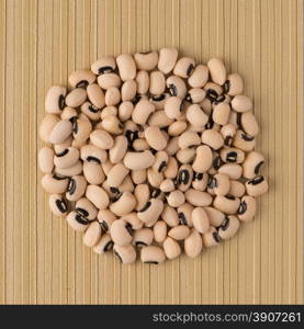 Top view of circle of white beans against yellow vinyl background.