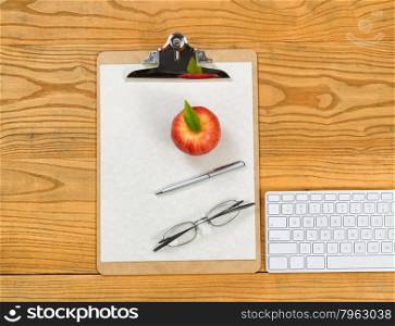 Top view of clipboard, computer keyboard, reading glasses, apple, paper and pen on desktop.