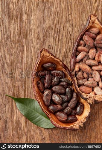 Top view of cocoa pods filled with raw unpeeled and peeled cocoa beans on wooden surface. Organic cocoa beans in halved pods