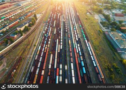 Top view of colorful cargo trains. Aerial view from flying drone of colorful freight trains on the railway station. Wagons with goods on railroad. Heavy industry. Industrial conceptual scene