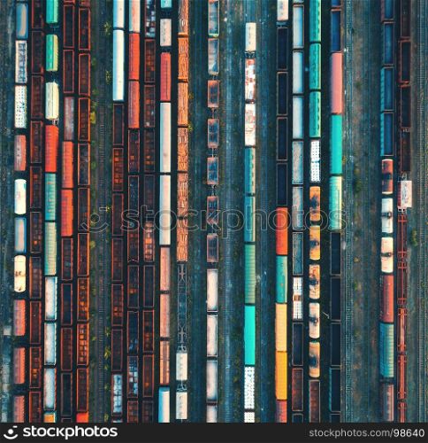 Top view of colorful cargo trains. Aerial view from flying drone of colorful freight trains on the railway station. Wagons with goods on railroad. Heavy industry. Industrial conceptual scene