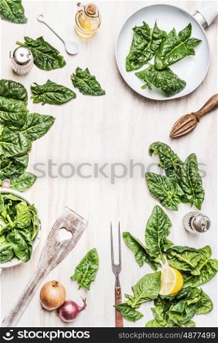 Top view of cooking preparation with green organic spinach leaves , ingredients and kitchen tools on white wooden background. Vegan or vegetarian nutrition, diet, detox and healthy food concept