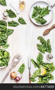 Top view of cooking preparation with green organic spinach leaves , ingredients and kitchen tools on white wooden background. Vegan or vegetarian nutrition, diet, detox and healthy food concept