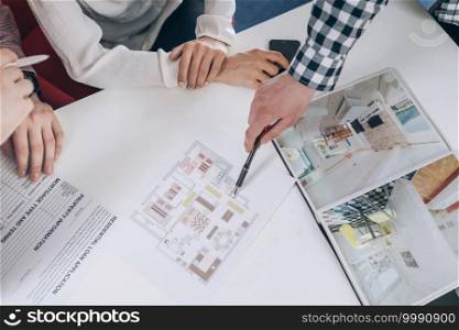 Top view of couple in real-estate agency looking at a model of their new home. . Real-Estate Agency Meeting Top View 