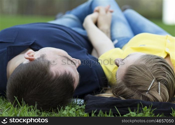 Top view of couple lying on the grass with heads together