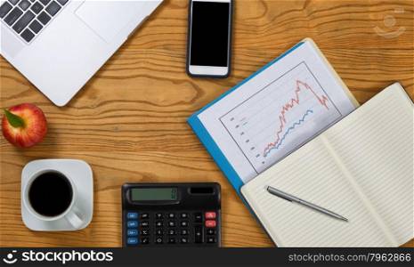Top view of desktop with financial working documents, computer and snacks. Stock market concept.