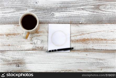 Top view of desktop with paper notepad, pen and coffee to include stain