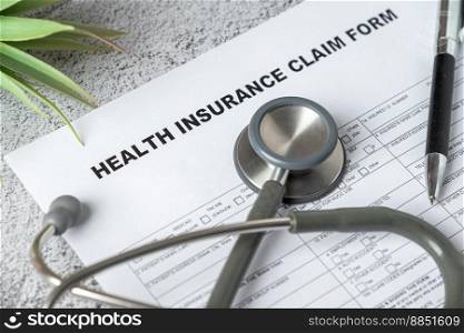 Top view of doctor stethoscope, pen and health insurance claim form on table