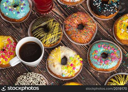 Top view of donuts in various colors and flavors on wooden table