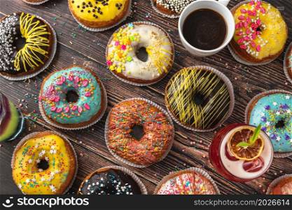 Top view of donuts in various colors and flavors on wooden table
