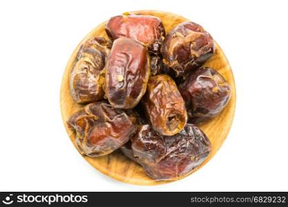 Top view of dried dates fruit in a wooden plate on white background