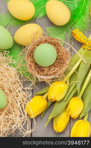 Top view of easter yellow tulips and eggs over wooden table