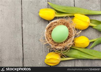 Top view of easter yellow tulips and eggs over wooden table