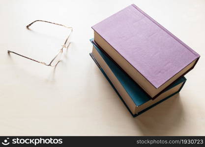 top view of eyeglasses and two blank books on light brown wooden board