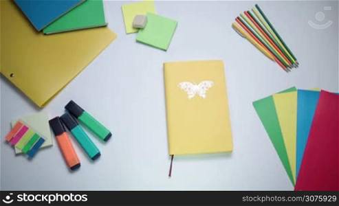 Top view of female hand opening notepad page with written word Idea on white table with office accessories on it