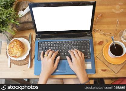 Top view of female using her laptop at a cafe. Overhead shot of young woman sitting at a table with a cup of coffee