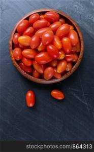 Top view of Fresh cherry tomatoes on bowl wooden with white wall background.
