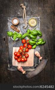 Top view of fresh cherry tomatoes with basil and olive oil on rustic background. Ingredients for tasty Italan food.