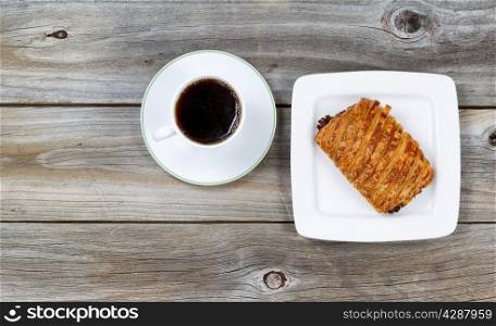 Top view of fresh hot coffee and baked chocolate filled croissant on vintage wood